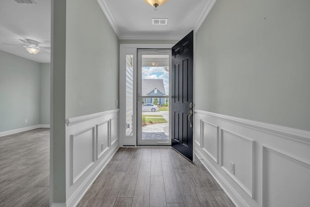 entrance foyer with ceiling fan, a wealth of natural light, crown molding, and light hardwood / wood-style flooring