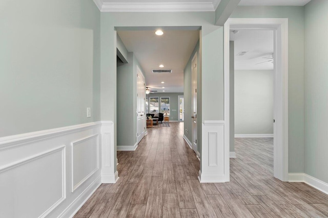 hall featuring light wood-type flooring, ornamental molding, and ornate columns