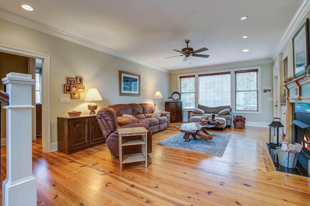 living area with light wood-style flooring, a ceiling fan, baseboards, a fireplace with flush hearth, and recessed lighting