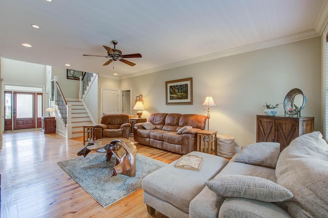 living room featuring stairway, light wood-type flooring, ornamental molding, ceiling fan, and recessed lighting