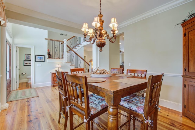dining room with a chandelier, light wood-style floors, ornamental molding, stairs, and baseboards