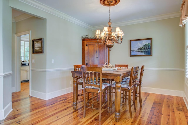 dining space with light wood-style flooring, a chandelier, ornamental molding, and baseboards