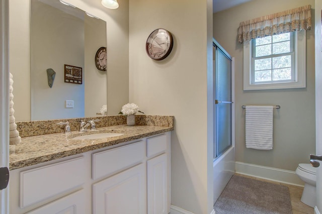bathroom featuring toilet, vanity, baseboards, tile patterned flooring, and combined bath / shower with glass door