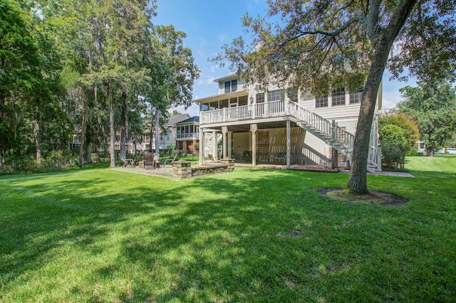 rear view of house with stairway, a sunroom, a lawn, a patio area, and a deck