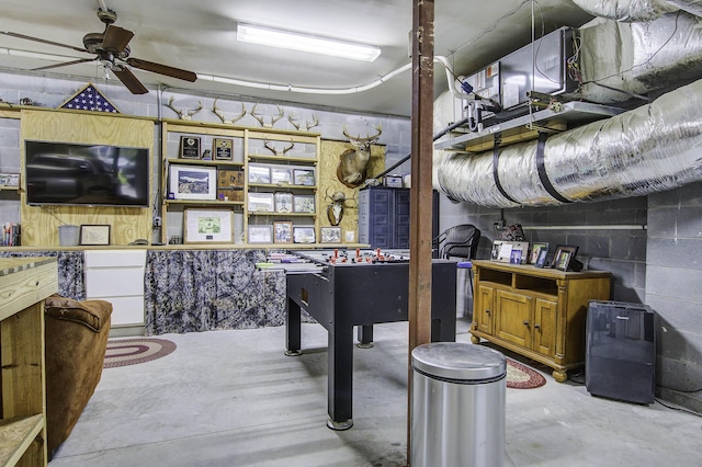 basement featuring a ceiling fan and concrete block wall