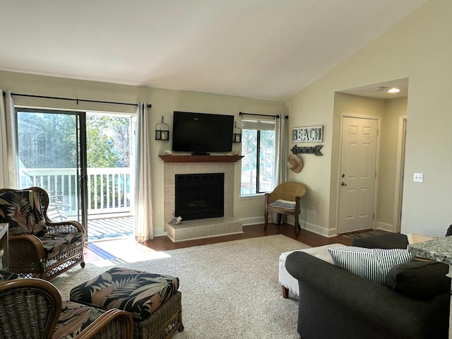 living room with hardwood / wood-style flooring, a tiled fireplace, and lofted ceiling