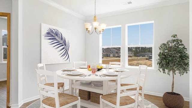 dining area with baseboards, visible vents, ornamental molding, wood finished floors, and an inviting chandelier