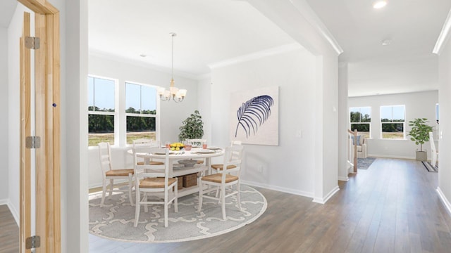 dining area featuring dark wood-type flooring, crown molding, baseboards, and an inviting chandelier