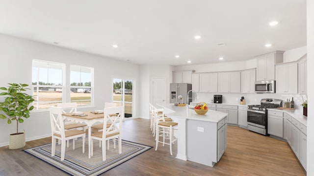 kitchen with stainless steel appliances, light countertops, an island with sink, and white cabinetry