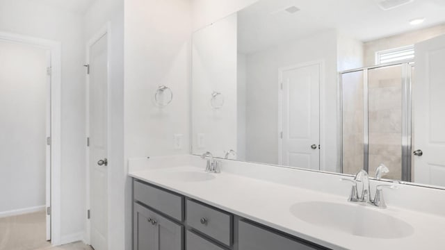 full bathroom featuring a stall shower, a sink, baseboards, and double vanity