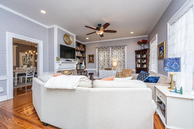 living room with recessed lighting, ceiling fan with notable chandelier, crown molding, and wood finished floors