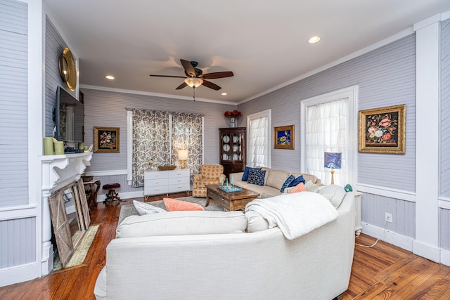 living area with a fireplace with flush hearth, crown molding, wood finished floors, and ceiling fan