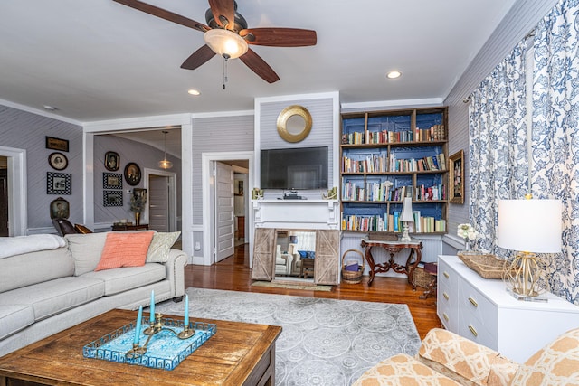 living room featuring a ceiling fan, recessed lighting, ornamental molding, and wood finished floors