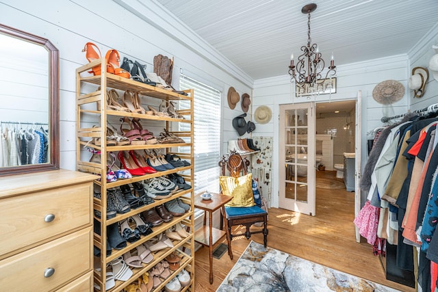 walk in closet featuring wood finished floors, french doors, and an inviting chandelier