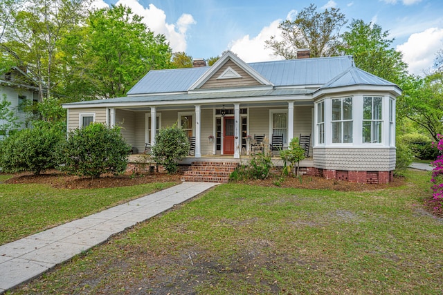view of front of home featuring metal roof, crawl space, a front lawn, a porch, and a chimney