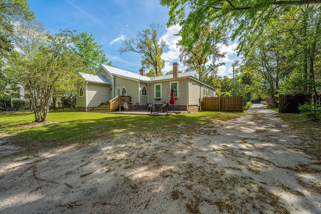 view of front of house with metal roof, fence, a chimney, and a front yard