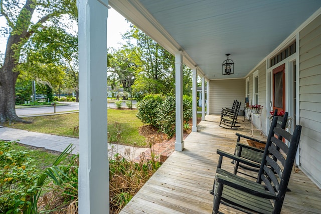 wooden terrace featuring a lawn and covered porch