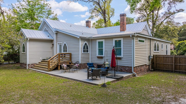 back of property featuring fence, metal roof, a patio area, a yard, and a chimney