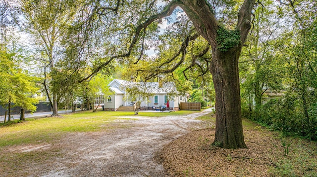 view of front of house with driveway, a front yard, and fence