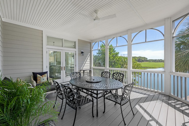 sunroom featuring a wealth of natural light, french doors, ceiling fan, and a water view