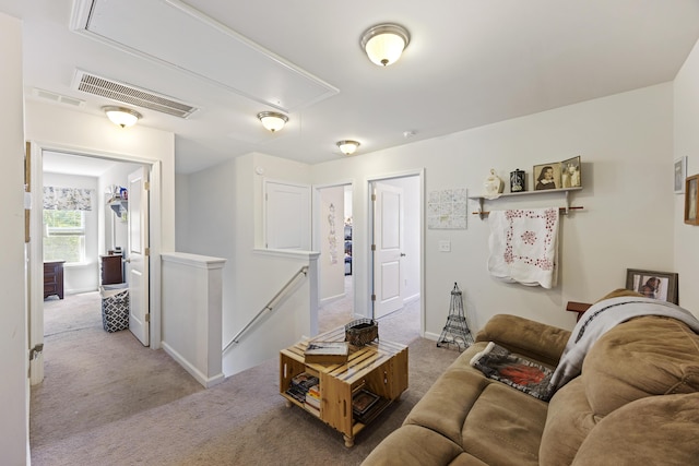 carpeted living area featuring baseboards, visible vents, and attic access