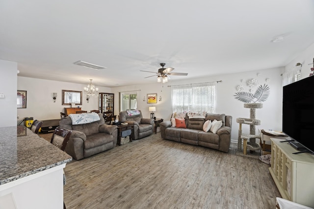living area featuring ceiling fan with notable chandelier, wood finished floors, and visible vents