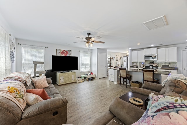 living room featuring recessed lighting, ceiling fan, visible vents, and light wood-type flooring