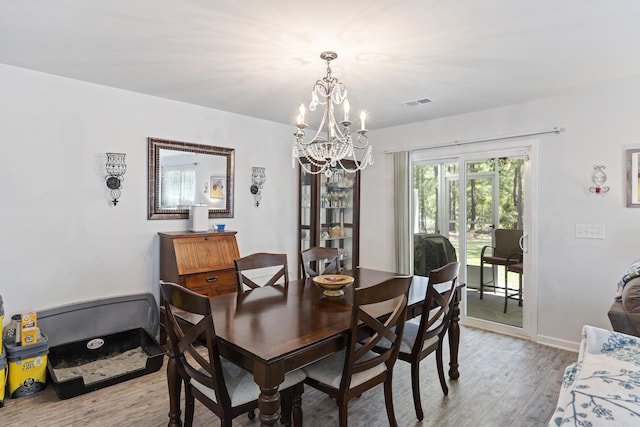 dining space with baseboards, visible vents, light wood finished floors, and a chandelier