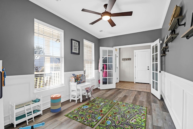 playroom with crown molding, hardwood / wood-style floors, ceiling fan, and french doors