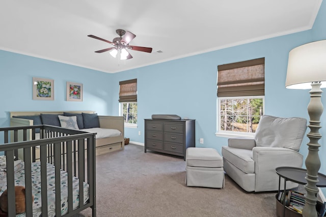 bedroom featuring ornamental molding, a nursery area, light carpet, and ceiling fan