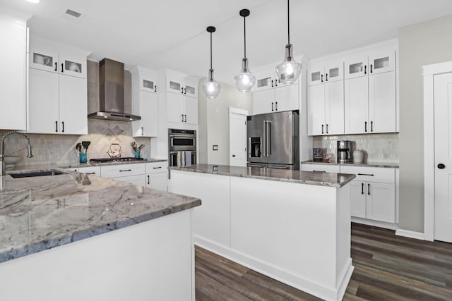 kitchen with white cabinetry, stainless steel appliances, a center island, and wall chimney range hood