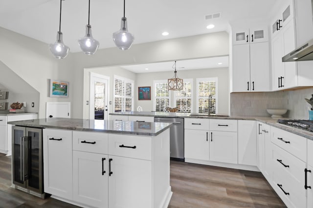 kitchen with pendant lighting, sink, stainless steel appliances, white cabinets, and beverage cooler