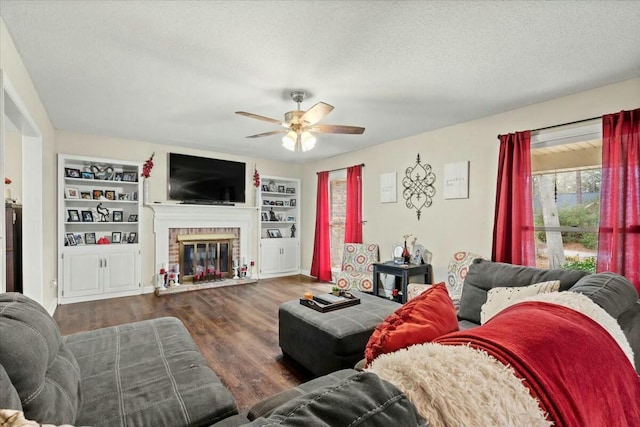 living room with dark wood-type flooring, built in features, ceiling fan, a fireplace, and a textured ceiling