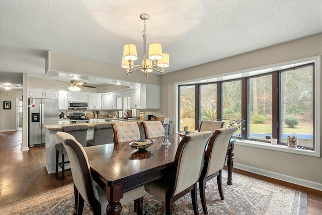 dining space with dark hardwood / wood-style floors, ceiling fan with notable chandelier, and a textured ceiling