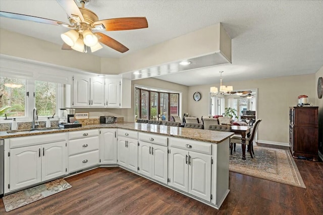 kitchen with sink, light stone countertops, kitchen peninsula, and white cabinets