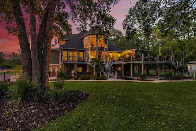 back house at dusk featuring a yard and a deck