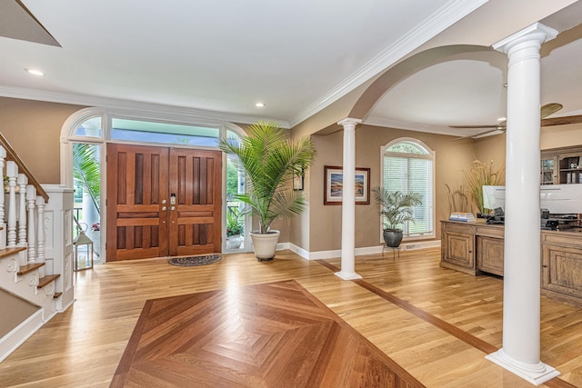 entryway featuring crown molding, light parquet floors, and ornate columns