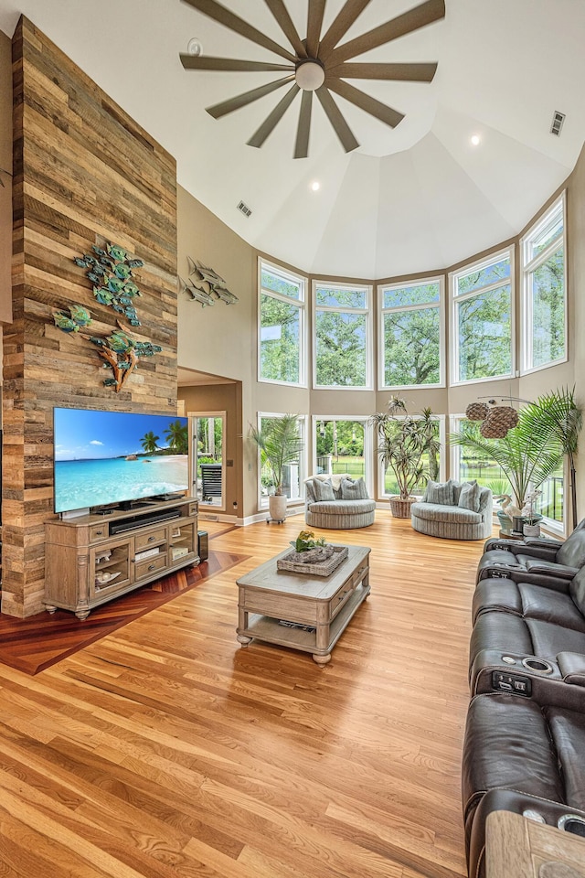 living room with ceiling fan, high vaulted ceiling, and light hardwood / wood-style flooring