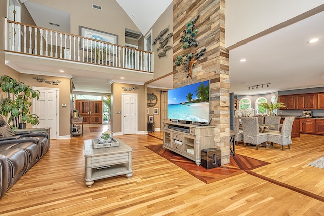 living room with crown molding, rail lighting, high vaulted ceiling, and light hardwood / wood-style flooring