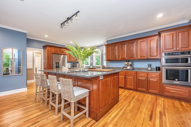 kitchen with a kitchen bar, light hardwood / wood-style flooring, a center island, and appliances with stainless steel finishes