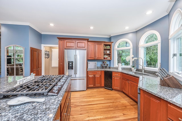 kitchen featuring sink, stainless steel appliances, a wealth of natural light, stone countertops, and light wood-type flooring