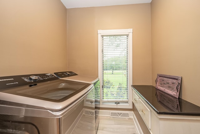 washroom featuring light tile patterned flooring, cabinets, and washing machine and dryer