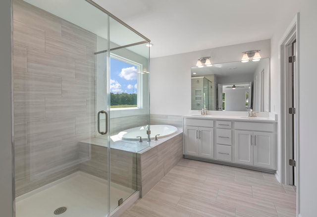 bathroom with plus walk in shower, ceiling fan, and vanity