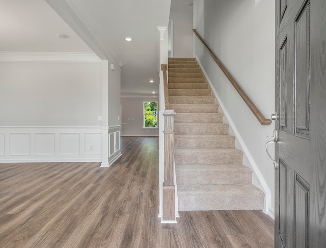 stairs with hardwood / wood-style flooring and crown molding