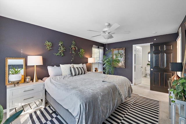 bedroom with connected bathroom, light colored carpet, and ceiling fan