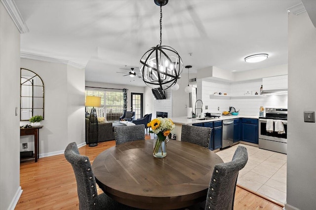 dining space featuring sink, a brick fireplace, crown molding, and light wood-type flooring