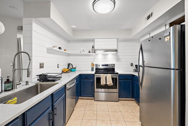 kitchen with appliances with stainless steel finishes, light tile patterned flooring, sink, blue cabinets, and exhaust hood