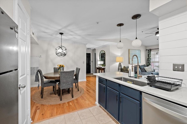 kitchen with blue cabinets, light hardwood / wood-style flooring, stainless steel appliances, sink, and decorative light fixtures