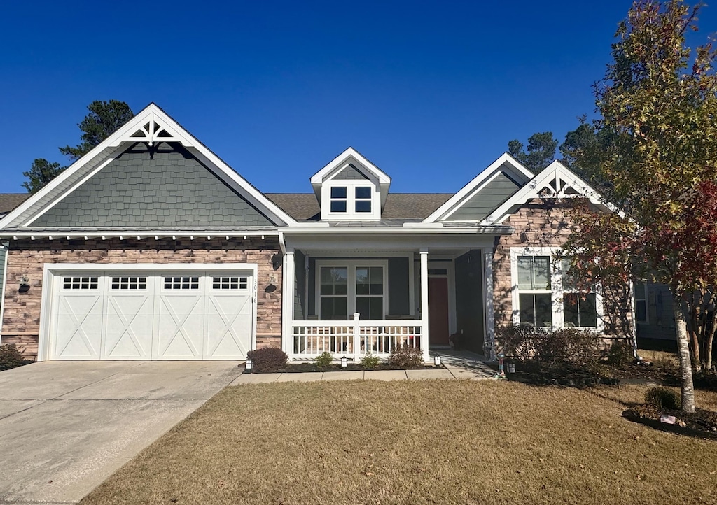 craftsman-style home with a porch, a garage, and a front yard