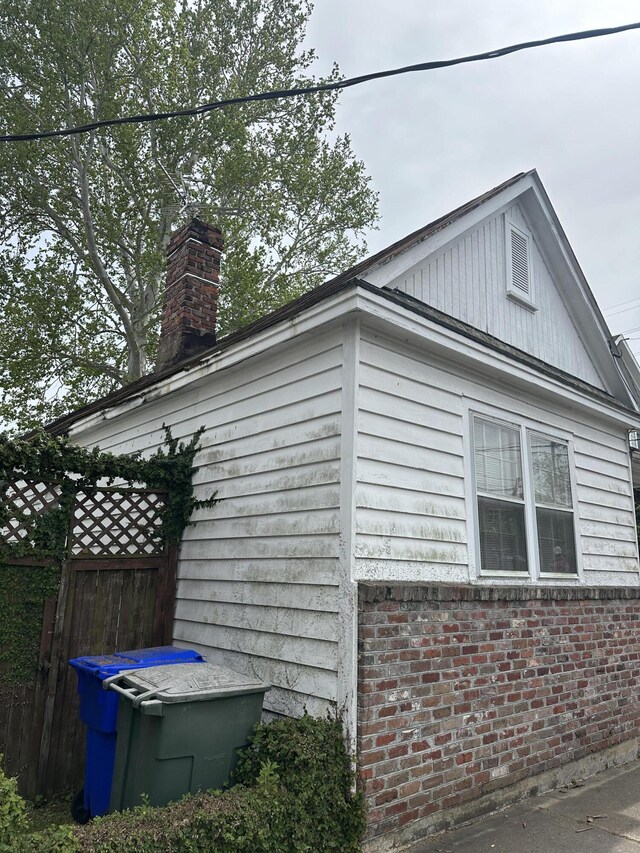 227 Fishburne St, Charleston, SC 29403 - view of property exterior featuring fence, brick siding, and a chimney